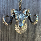 Sterling silver ram head pendant on a dark wooden background
