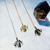 Three ram head necklaces on a marble surface with a crystal.