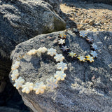 Mother of pearl flower bracelets resting on a grey beach rock.