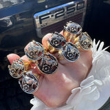 Hand wearing multiple horseshoe rings on against a black ford f-250 pick up truck.