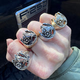 Hand wearing multiple horseshoe rings on against a black f-250 pick up truck.