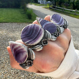 Hand wearing 4 sterling silver wampum ring against stone driveway.