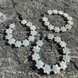 Floral shaped white mother of pearl bracelets on a textured stone surface
