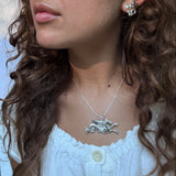 Close-up of a girl with curly hair wearing a pair of  hippocampus earrings and a hippocampus necklace both in sterling silver.