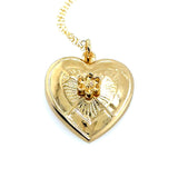 Gold heart-shaped pendant with two swords crossing design on a white background