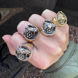 Hand wearing multiple horseshoe rings on against a black pick up truck.