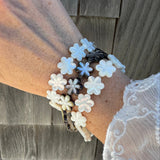 Hand wearing a floral bracelet against a wooden background