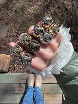 Hand wearing multiple horseshoe rings on against long legs.