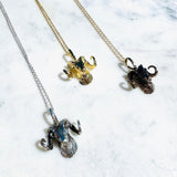 Three ram head pendants on chains against a marble background.