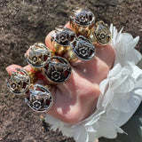 Hand wearing multiple horseshoe rings on against a neutral background