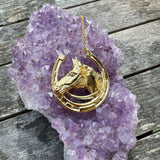 Gold horseshoe necklace on a purple amethyst crystal rock