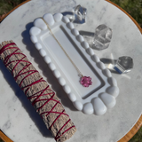 Jewelry dish with necklace, crystals, and sage on a marble surface