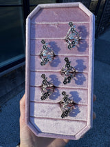 Jewelry tray with silver flower rings held by a hand on a pink velvet ring tray.