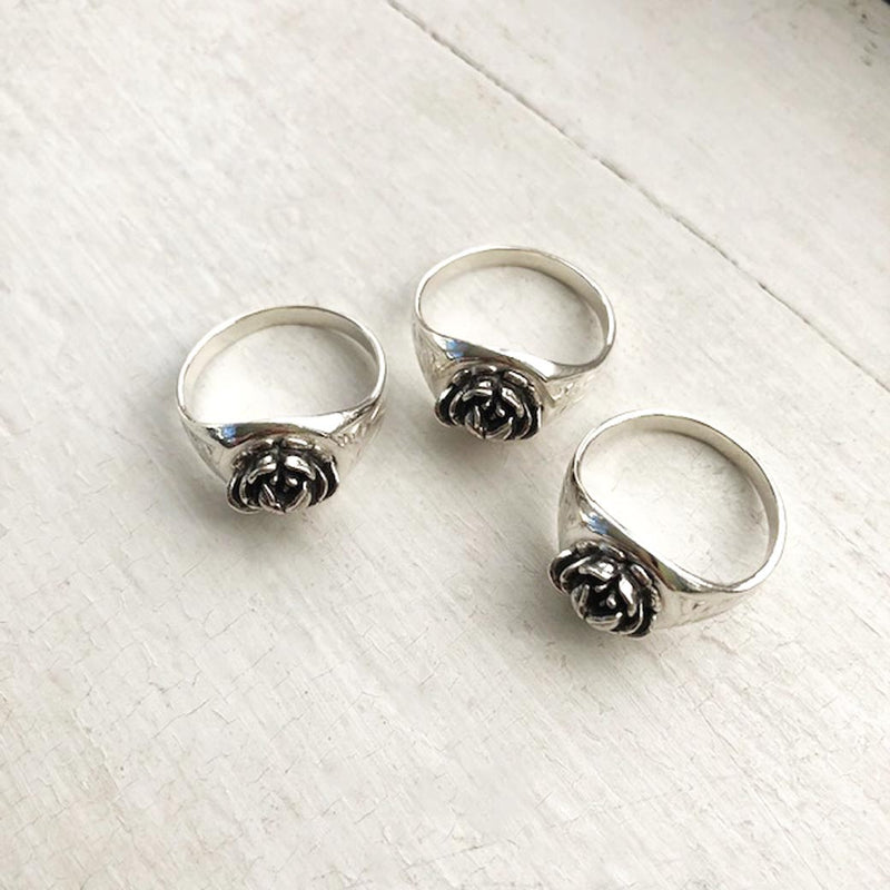 three silver rose signet rings on white window sill 