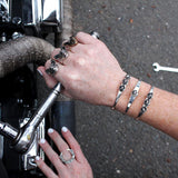 two hands fixing Harley Davidson with handmade sterling silver jewelry